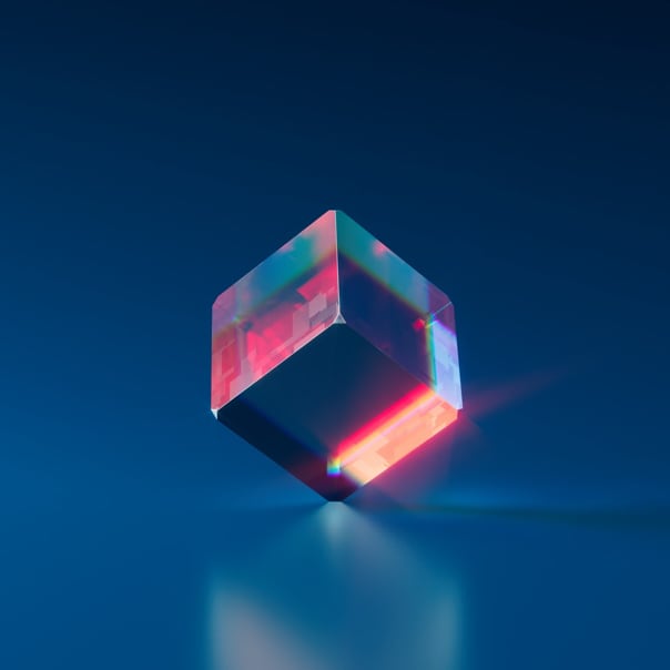 imagem de um cubo colorido no centro da imagem. O cubo está em euilibrio, existe um equilibroi embaixo do mesmo, como se tivesse uma luz em encima do cubo